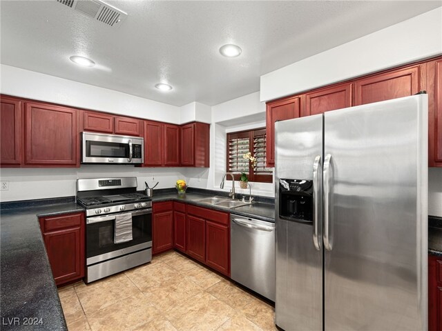 kitchen with a textured ceiling, sink, and appliances with stainless steel finishes