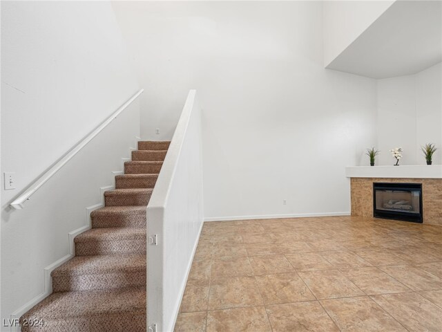 staircase with tile patterned floors and a tile fireplace