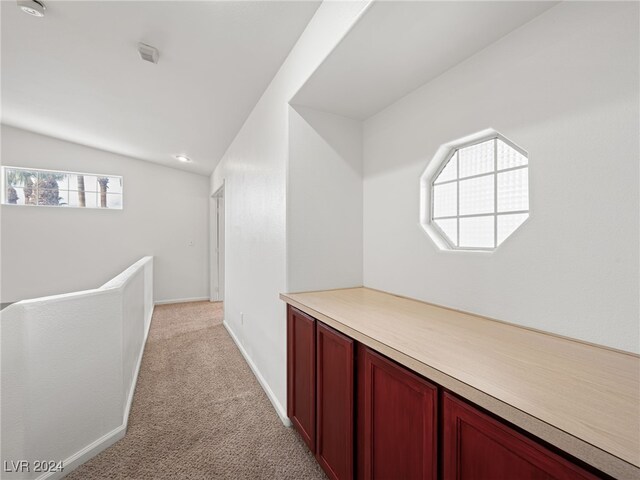 hallway featuring light carpet and vaulted ceiling