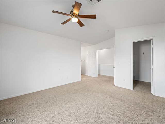 unfurnished bedroom featuring ceiling fan, a closet, light carpet, and vaulted ceiling