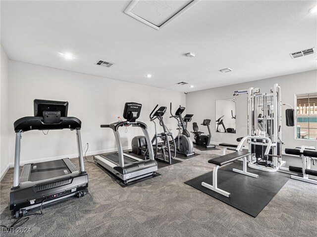 gym with a textured ceiling and dark carpet