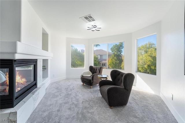 living area with a high end fireplace and light carpet