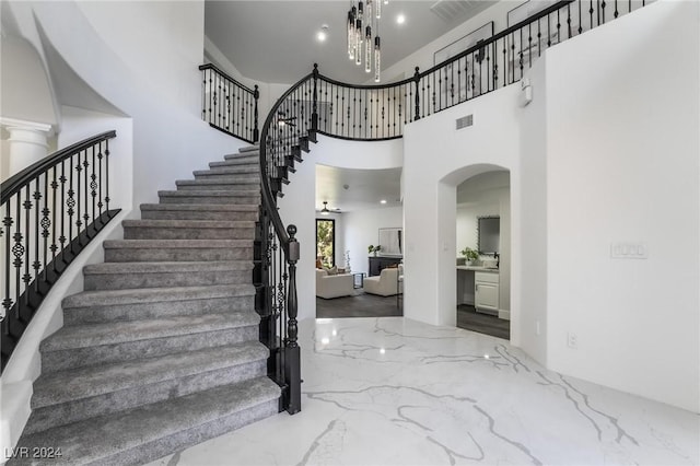 foyer entrance with a high ceiling and ceiling fan with notable chandelier