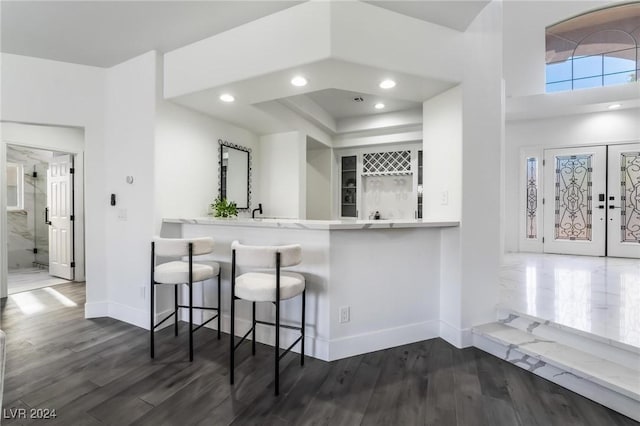 kitchen with a kitchen bar, french doors, dark hardwood / wood-style flooring, and kitchen peninsula