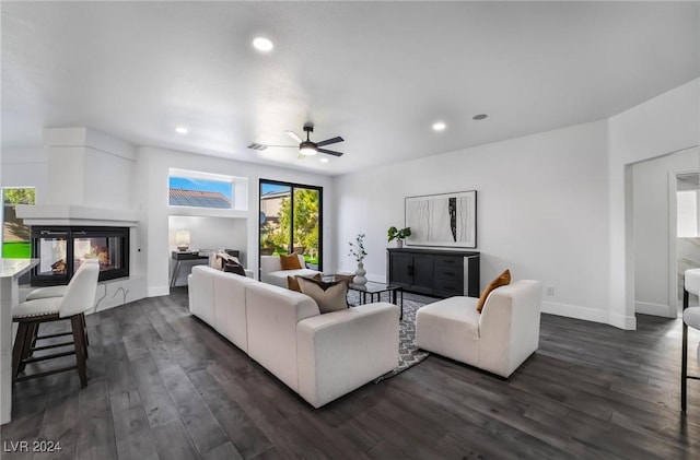 living room featuring dark hardwood / wood-style floors, ceiling fan, and a multi sided fireplace