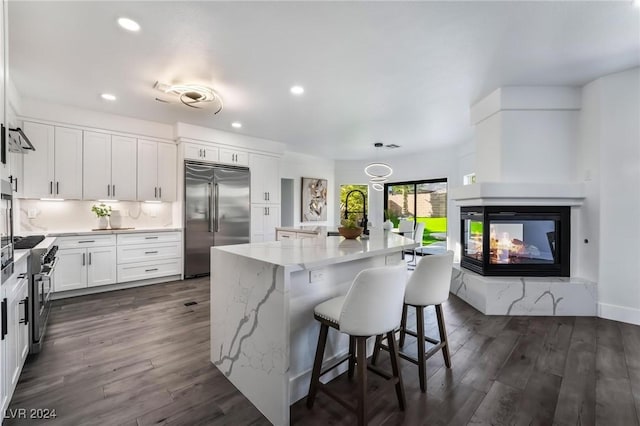 kitchen with white cabinets, a center island, dark hardwood / wood-style floors, and high quality appliances