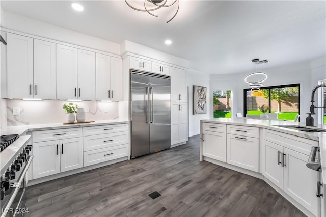 kitchen with white cabinetry, sink, dark hardwood / wood-style flooring, decorative backsplash, and high end appliances