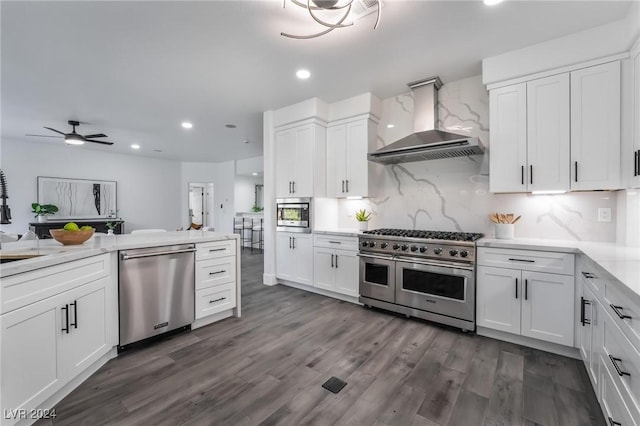 kitchen with white cabinetry, wall chimney exhaust hood, stainless steel appliances, tasteful backsplash, and dark hardwood / wood-style flooring