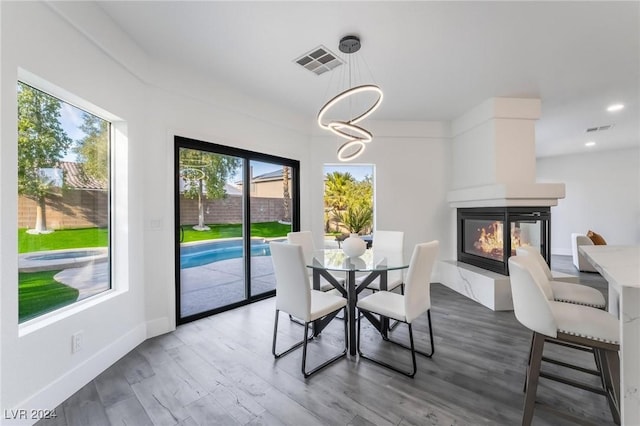 dining space featuring a multi sided fireplace, hardwood / wood-style floors, and a notable chandelier