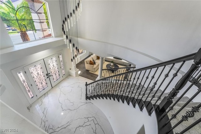 stairway with decorative columns, a high ceiling, and french doors