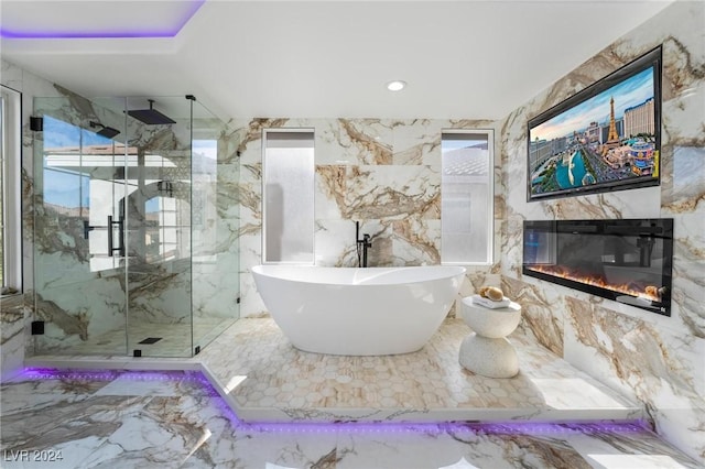 bathroom featuring plus walk in shower and tile walls