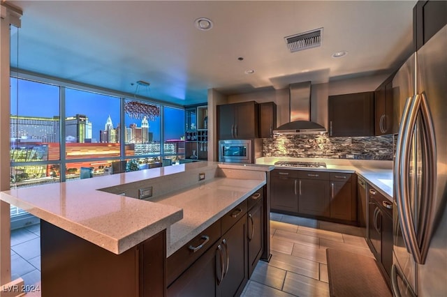 kitchen featuring backsplash, stainless steel appliances, plenty of natural light, and wall chimney range hood