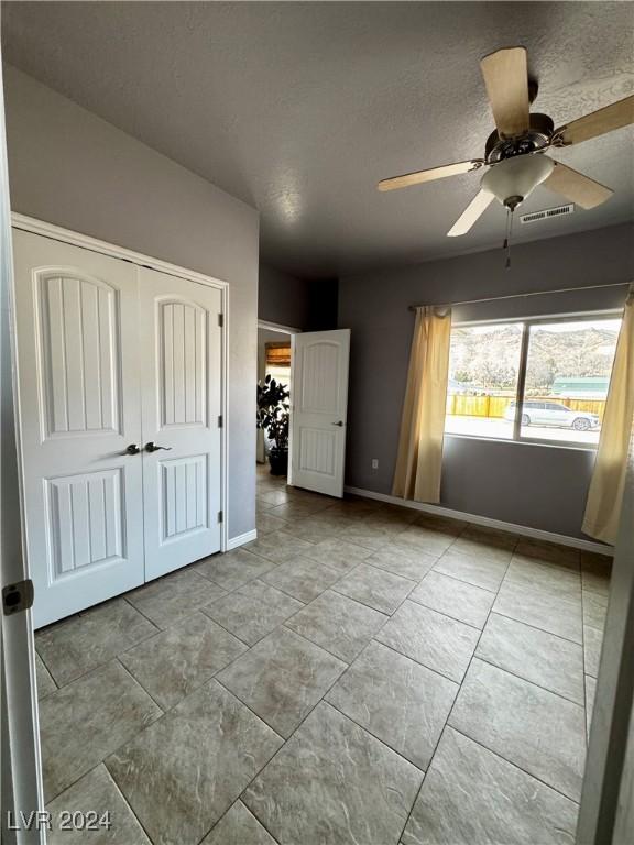 unfurnished bedroom featuring a textured ceiling, a closet, and ceiling fan