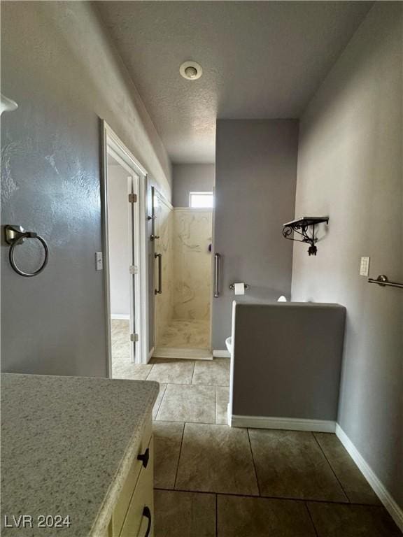 bathroom with tile patterned flooring, a textured ceiling, vanity, and an enclosed shower