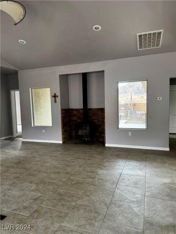 unfurnished living room with a wood stove and vaulted ceiling