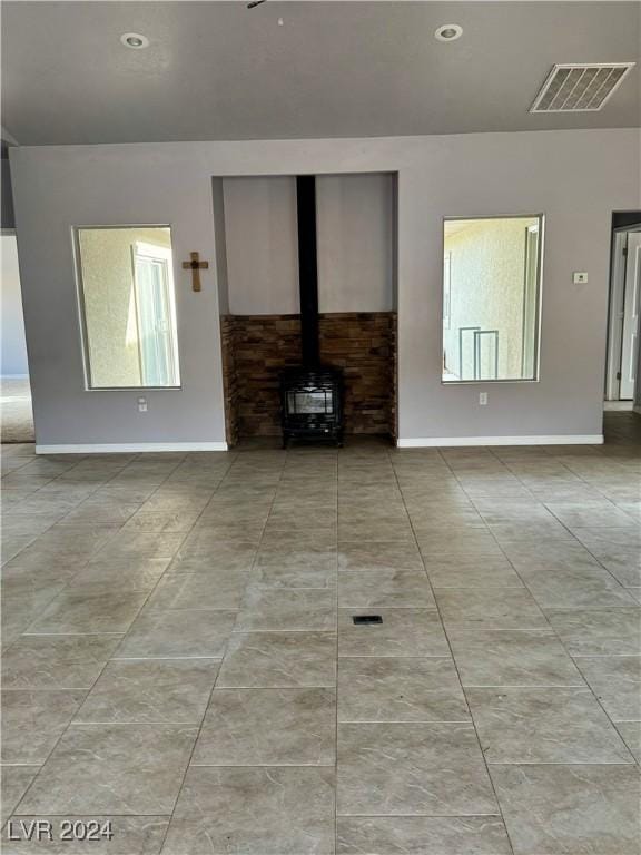 unfurnished living room with a wood stove and a healthy amount of sunlight