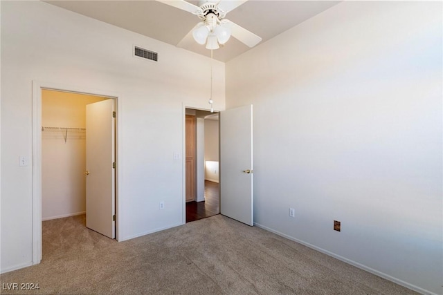 unfurnished bedroom featuring carpet, a closet, a spacious closet, and ceiling fan