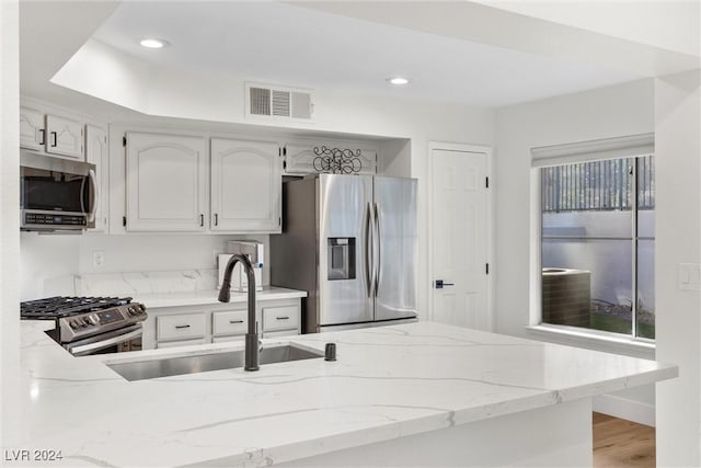 kitchen with stainless steel appliances, sink, white cabinets, and kitchen peninsula