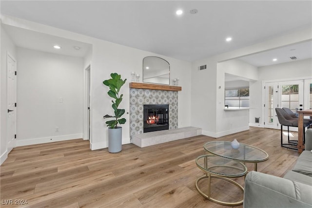 living room featuring french doors, a tile fireplace, and light hardwood / wood-style flooring