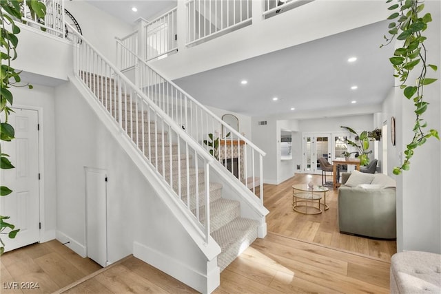 staircase with wood-type flooring, french doors, and a high ceiling