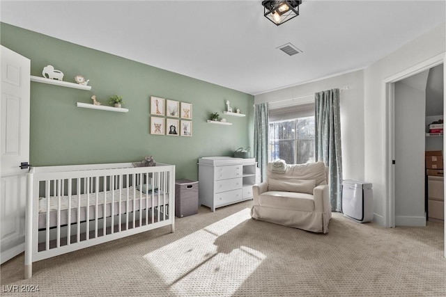 bedroom with a nursery area and carpet floors