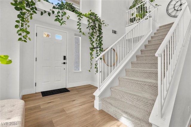 foyer with a towering ceiling and light hardwood / wood-style floors