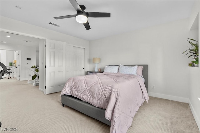 bedroom with light carpet, ceiling fan, and a closet