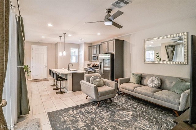 living room with ceiling fan, light tile patterned flooring, and sink