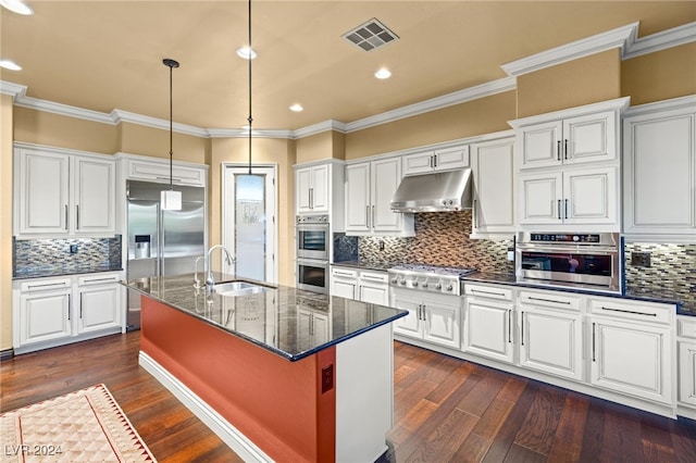 kitchen with dark wood-type flooring, a center island with sink, sink, dark stone countertops, and stainless steel appliances