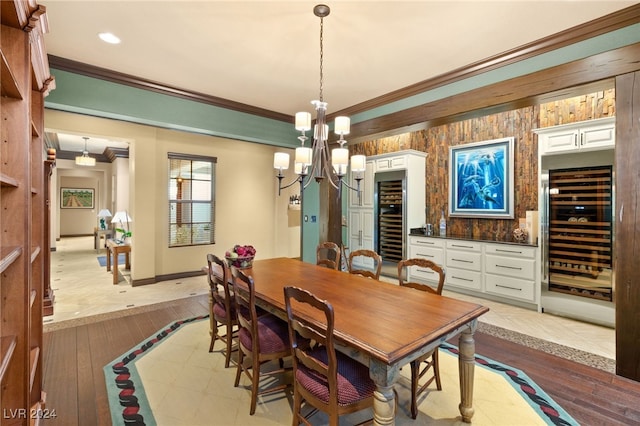 dining space featuring light wood-type flooring, an inviting chandelier, wine cooler, and crown molding