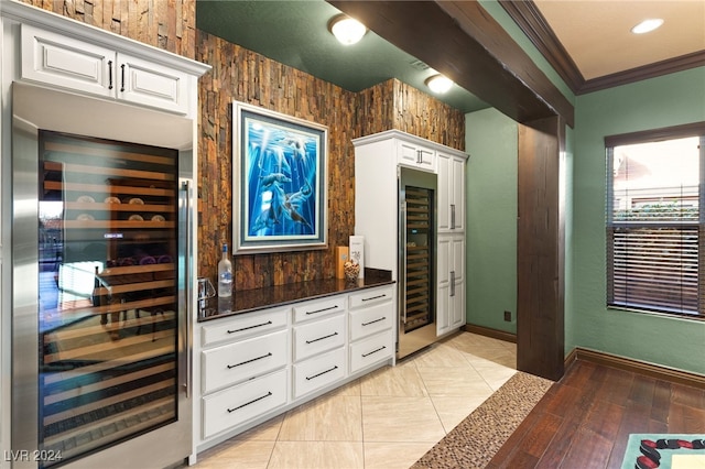 interior space with white cabinets, light hardwood / wood-style floors, dark stone countertops, and beverage cooler