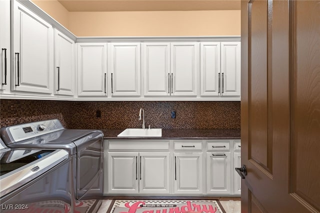 clothes washing area with separate washer and dryer, sink, and cabinets