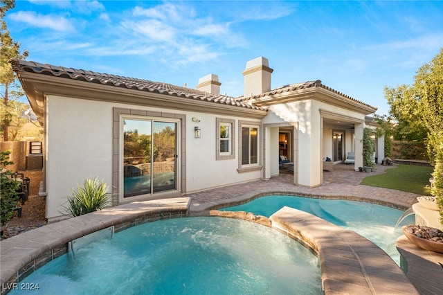 rear view of house with pool water feature, a swimming pool with hot tub, and a patio area