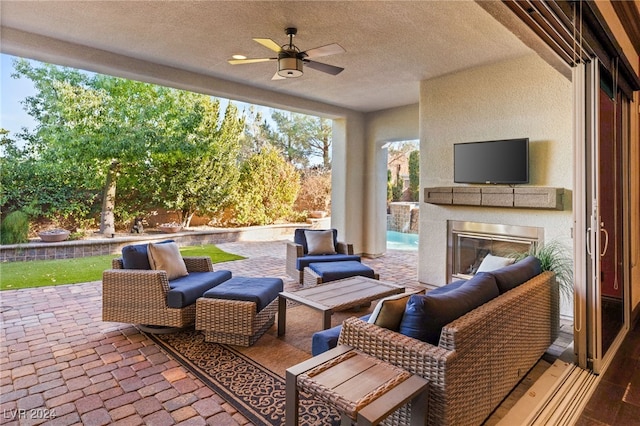 view of patio / terrace with an outdoor living space with a fireplace and ceiling fan