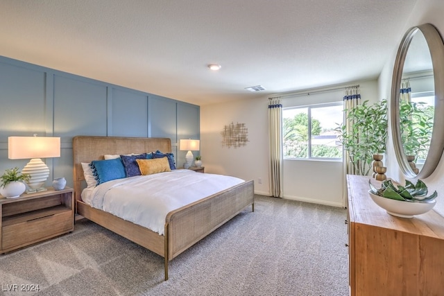 bedroom with a textured ceiling and light colored carpet