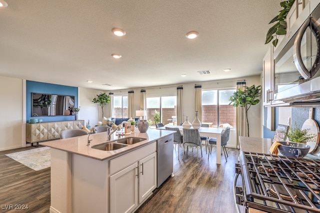 kitchen with dark wood-type flooring, white cabinets, sink, an island with sink, and appliances with stainless steel finishes