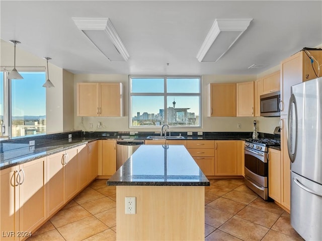 kitchen with dark stone countertops, a center island, sink, appliances with stainless steel finishes, and light brown cabinets