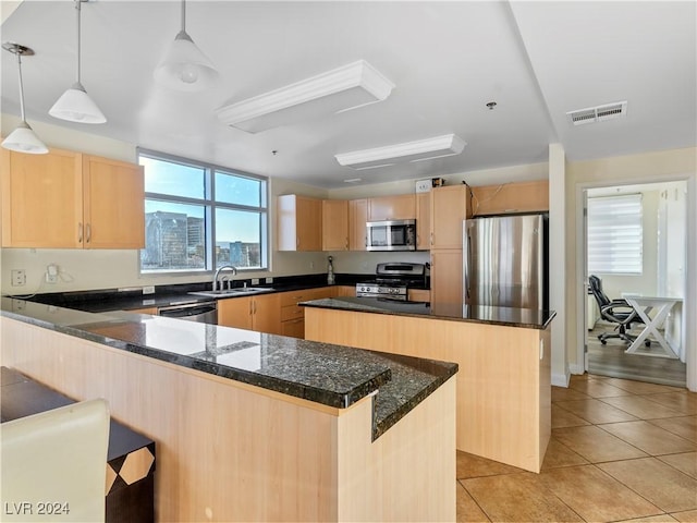 kitchen with decorative light fixtures, sink, stainless steel appliances, and a center island