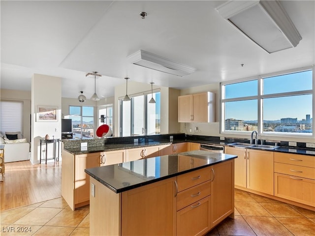 kitchen featuring plenty of natural light, light tile patterned floors, a center island, and sink