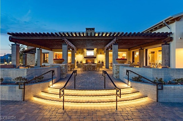 patio terrace at dusk with a pergola and exterior kitchen