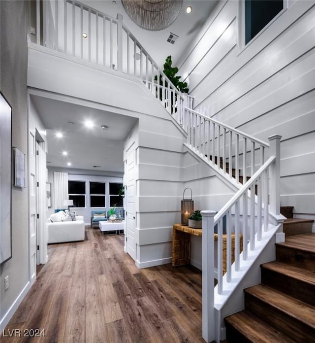 stairway with a towering ceiling and wood-type flooring