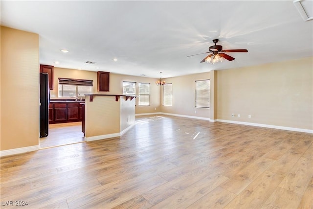 unfurnished living room featuring ceiling fan with notable chandelier, light hardwood / wood-style floors, and sink