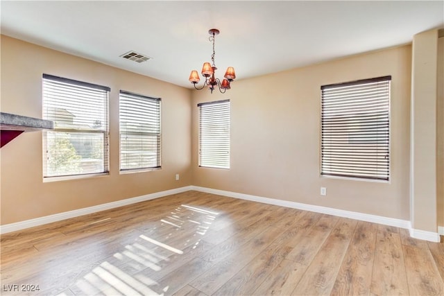 empty room with an inviting chandelier and light wood-type flooring