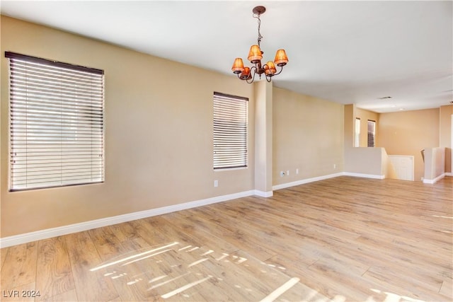 unfurnished room featuring a chandelier and hardwood / wood-style flooring