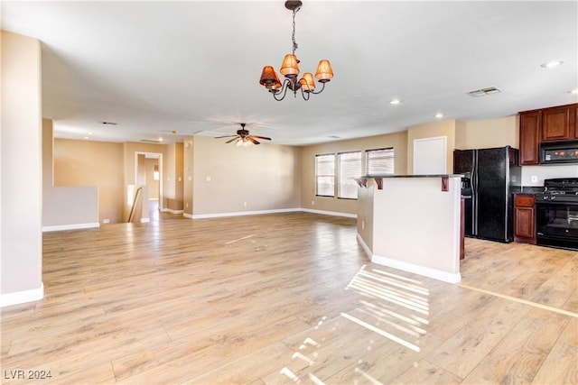 kitchen with black appliances, a breakfast bar, light wood-type flooring, and decorative light fixtures