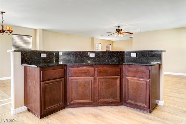 kitchen featuring a center island, dark stone counters, ceiling fan with notable chandelier, light hardwood / wood-style flooring, and decorative light fixtures