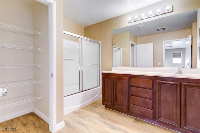 bathroom featuring vanity, enclosed tub / shower combo, and hardwood / wood-style flooring