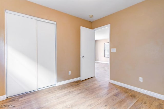 unfurnished bedroom with a closet and light hardwood / wood-style floors