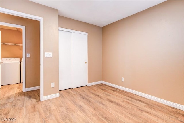 unfurnished bedroom with a closet, light hardwood / wood-style flooring, and washer and dryer