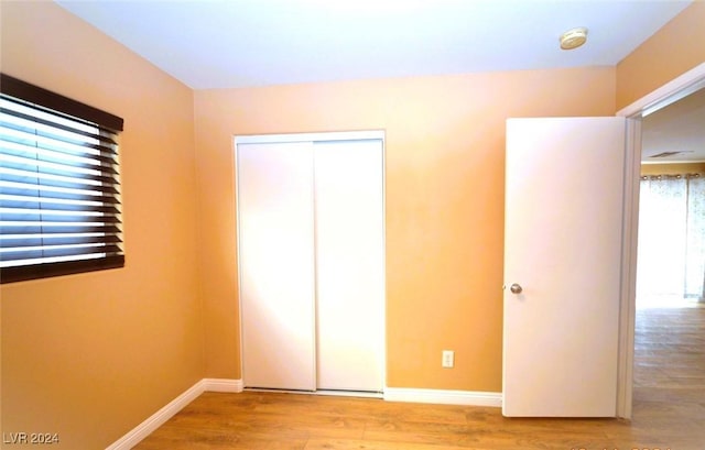 unfurnished bedroom featuring multiple windows, a closet, and light hardwood / wood-style floors